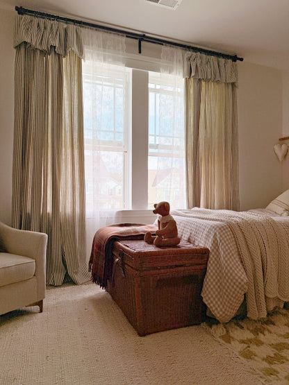 Bedroom with classic linen striped curtains in neutral tones, cozy bed, and rustic decor.