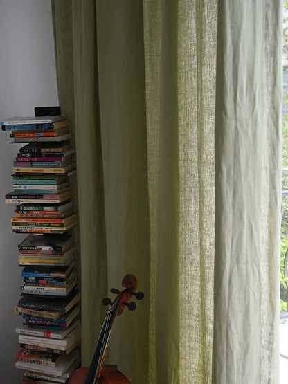 sage green linen curtains with natural texture in living room near stacked books and violin