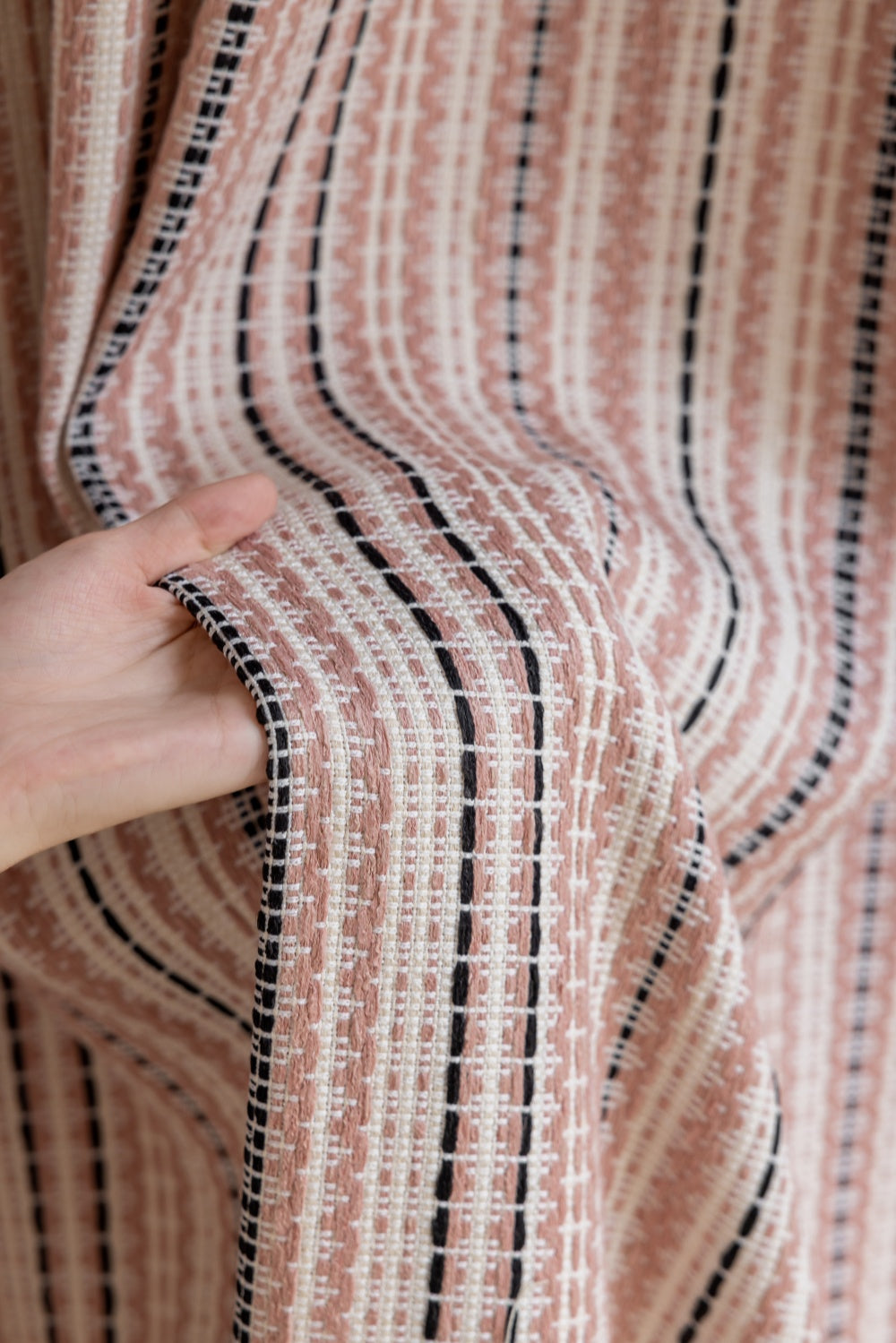 Striped curtains in pink and black jacquard fabric showcasing intricate patterns and texture.