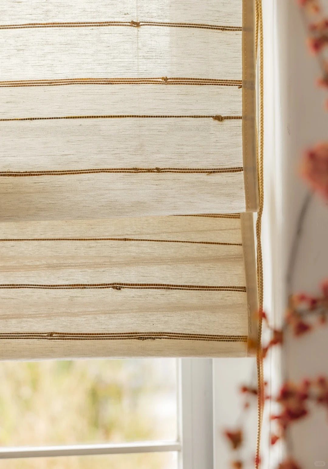 Natural ivory sand bamboo blinds with horizontal woven stripes, partially lowered on a window, showcasing breathable and mildew-resistant ramie fabric texture