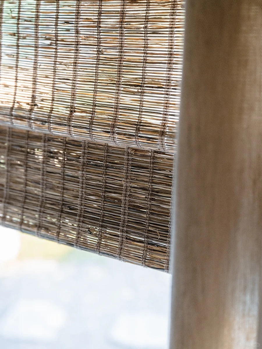 Natural jute bamboo shades in rich cinnamon color with handwoven Roman folds for outdoor use