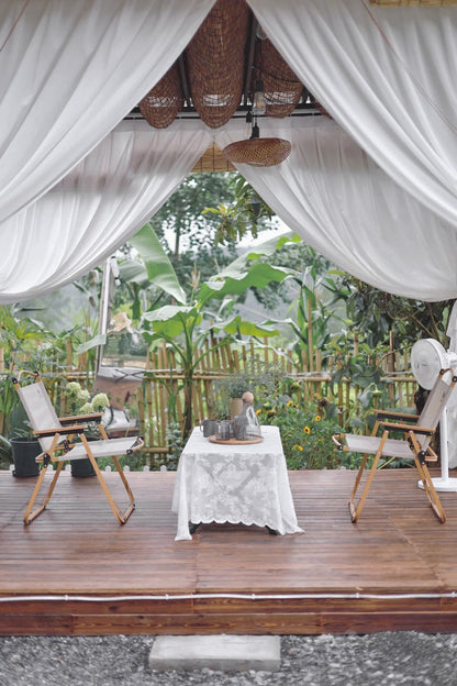 Outdoor curtains on a patio creating a light and airy ambiance with greenery in the background.