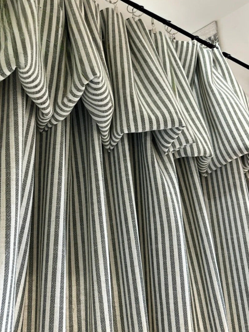 Close-up of classic linen striped curtains in neutral tones hanging elegantly with alternating fine and bold vertical stripes.