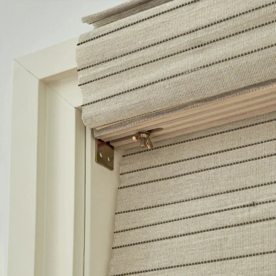 Natural linen bamboo shade with black stripes in window frame, eco-friendly design.