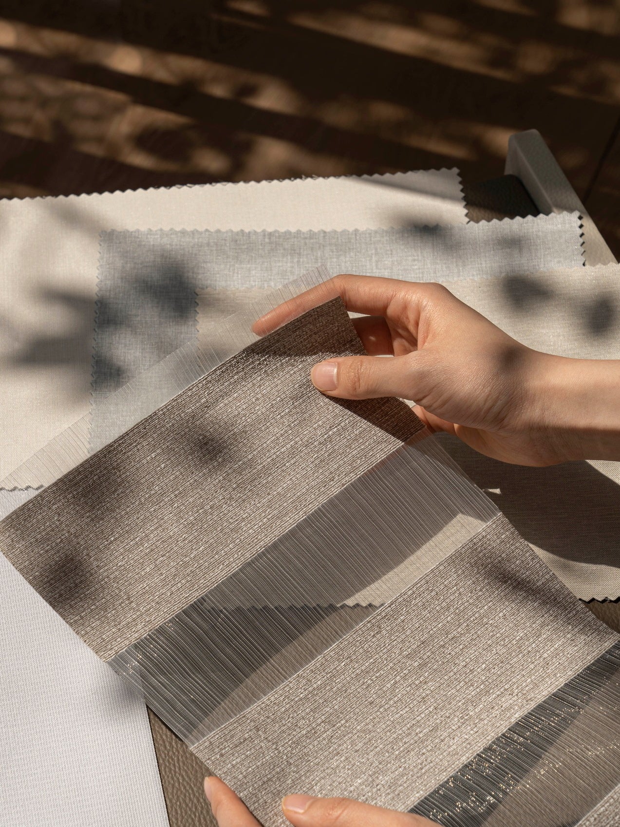 Customer evaluating texture and light-blocking qualities of curtain fabric samples from EaseEaseCurtains' free sample collection