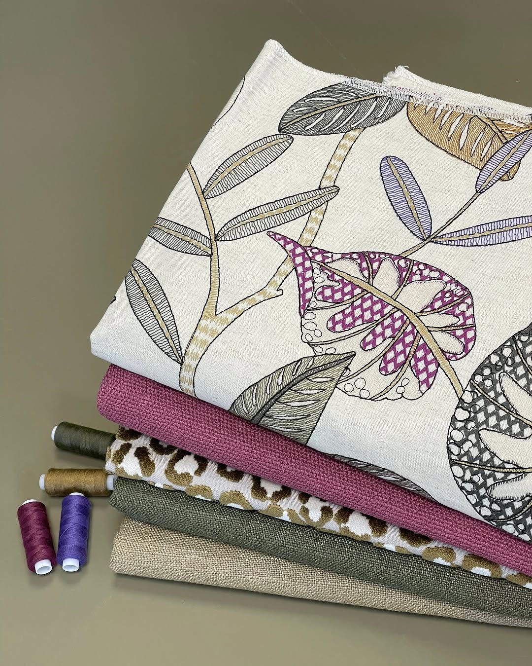 Patterned fabric Roman shades with threads, featuring various textures and colors for home decor.