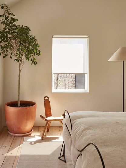 Cordless natural woven linen roller shades in a modern bedroom.