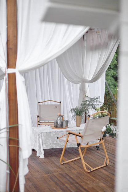 Outdoor curtains creating a breezy, elegant patio setting with sheer fabric allowing sunlight and air.