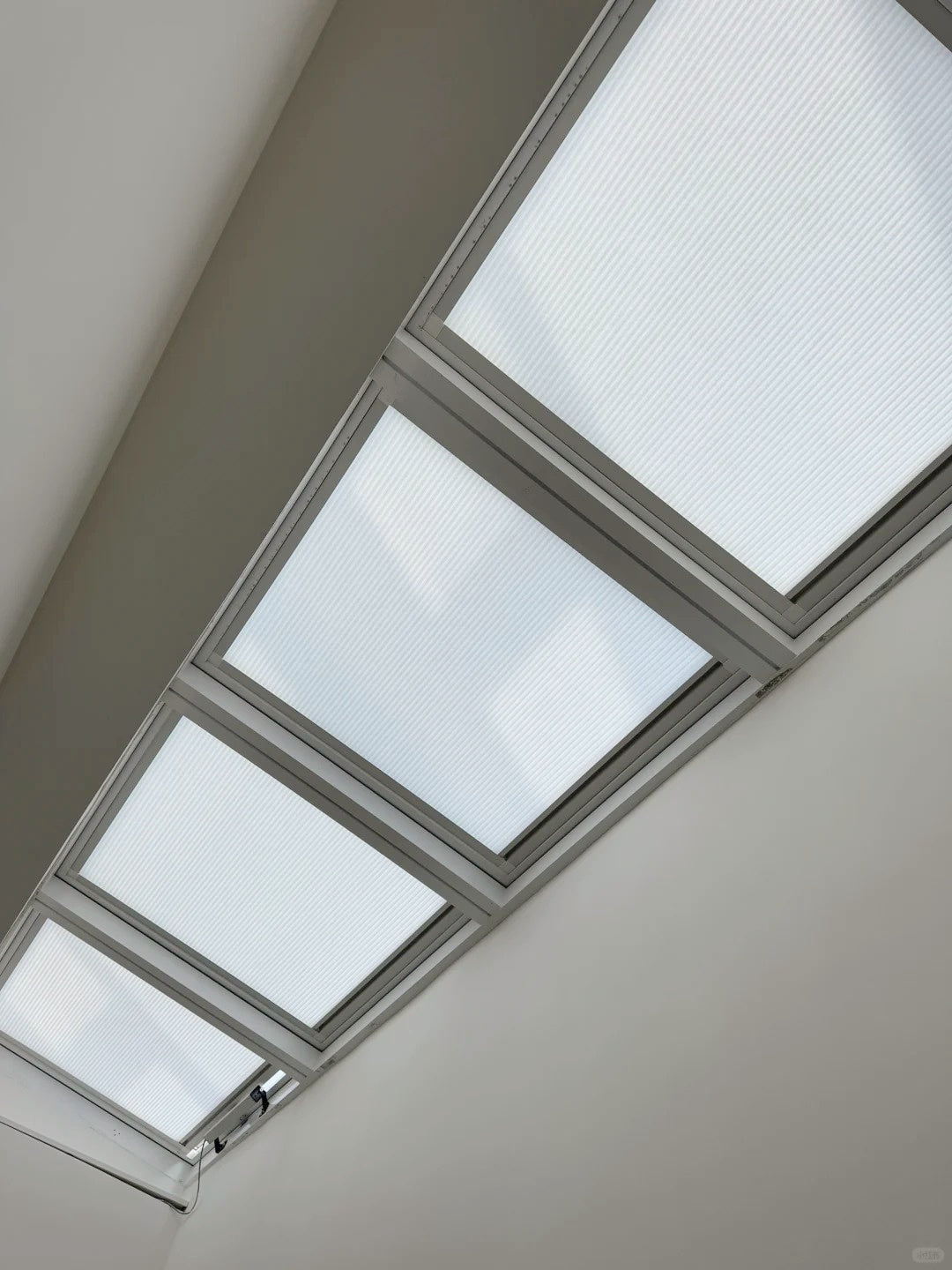 Skylight blinds with honeycomb cellular design installed on a sunroom ceiling.