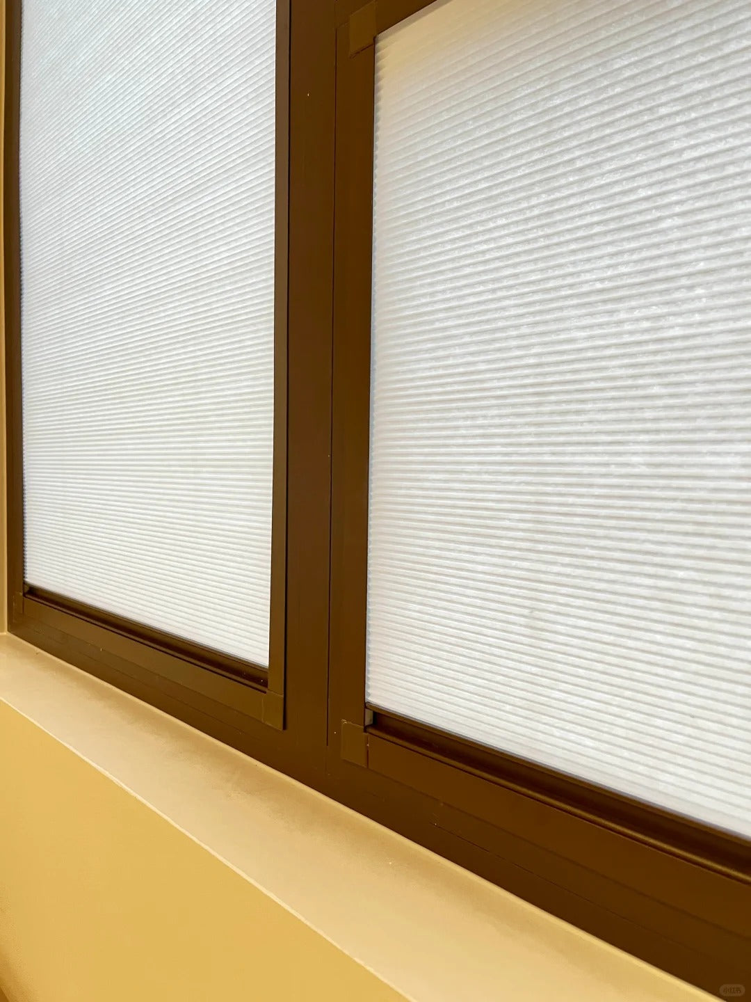 Close-up of 16mm honeycomb shades installed on a clear glass window, perfectly aligned with the window frame. The shades offer excellent privacy and feature a sophisticated, high-end color.