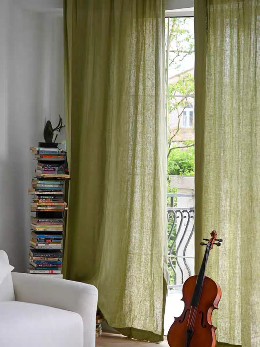 Eco-friendly sage green linen curtains hanging in a living room with natural light and a violin nearby