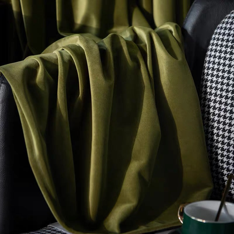 Luxurious high-matte olive green velvet drapes with creamy-soft texture on black leather chair