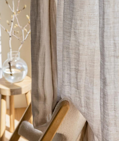 Elegant natural beige linen curtain from France draped over a wooden chair, highlighting luxurious texture and sophisticated home decor