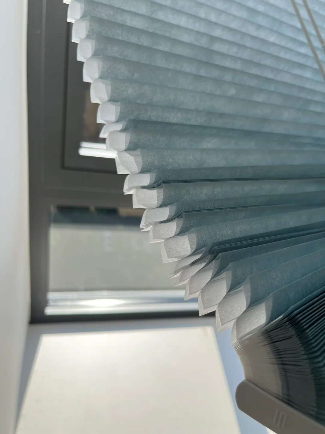 Close-up of light blue dual-cell honeycomb shades with large apertures, showcasing the intricate design and refreshing aesthetic.