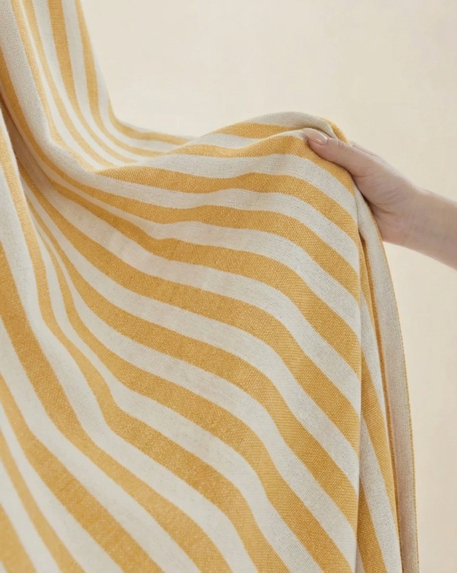Soft yellow striped linen playroom curtains hanging in a child's room with light filtering features