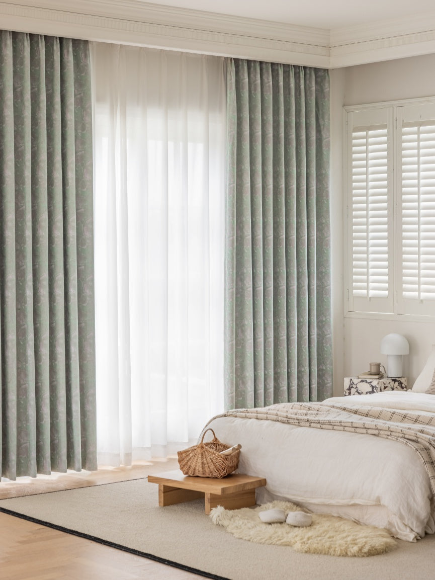 Elegant bedroom with green patterned blackout curtains and sheer white inner curtains from EaseEaseCurtains, enhancing a cozy and stylish interior decor