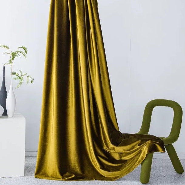 Luxurious high-matte velvet drapes in golden yellow with a soft, vintage texture elegantly hanging and pooling on the floor near a modern green chair in a minimalist room