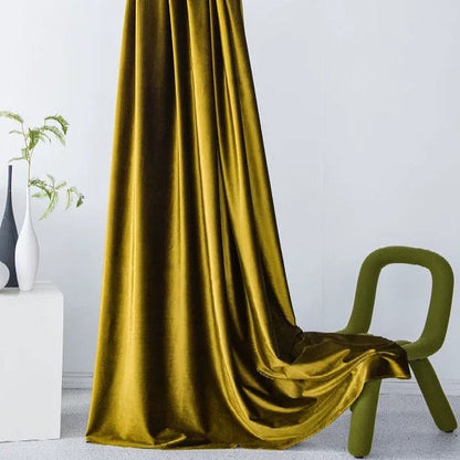 Luxurious high-matte velvet drapes in golden yellow with a soft, vintage texture elegantly hanging and pooling on the floor near a modern green chair in a minimalist room