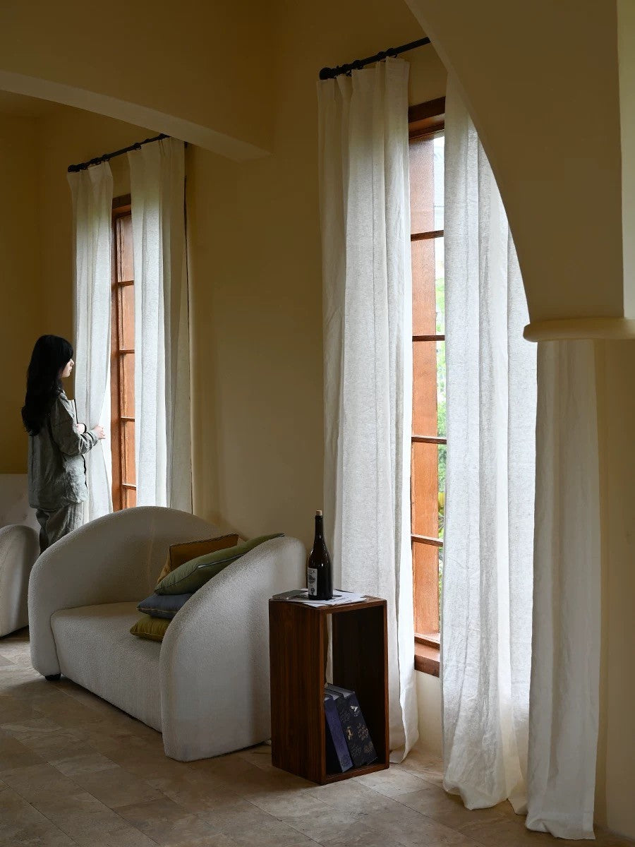 white sheer linen curtains hanging in living room with natural light filtering through large windows