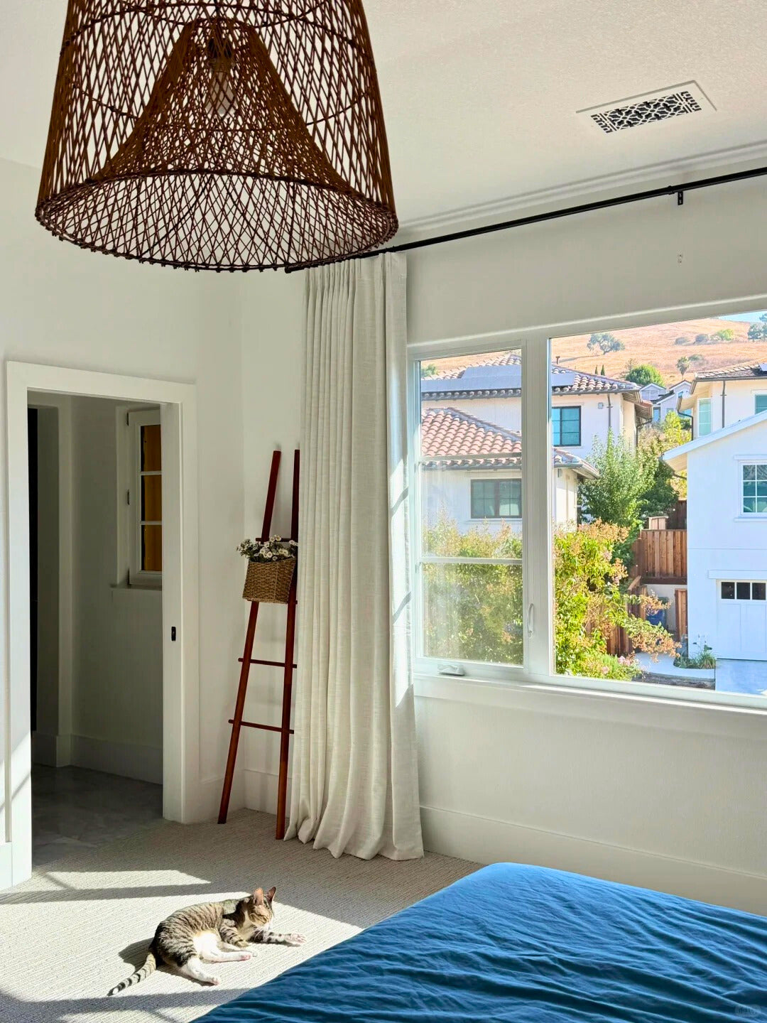 linen blackout curtains in bright bedroom with window and cat lounging on floor