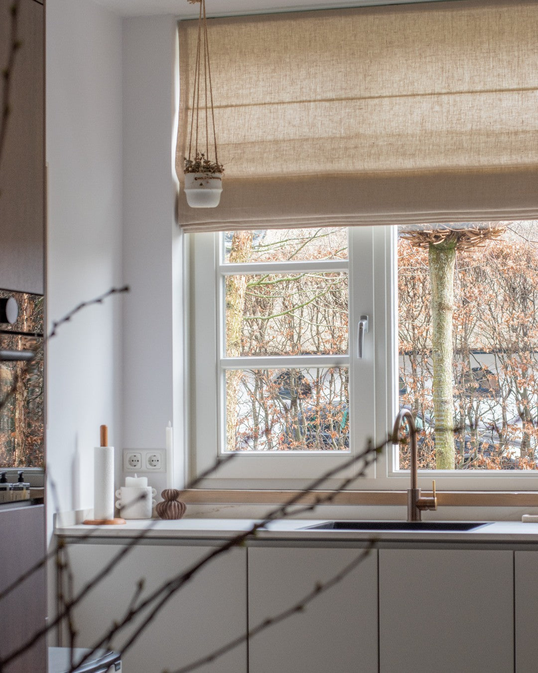 Custom Roman shades in a kitchen setting, light-filtering, cordless, eco-friendly fabric.