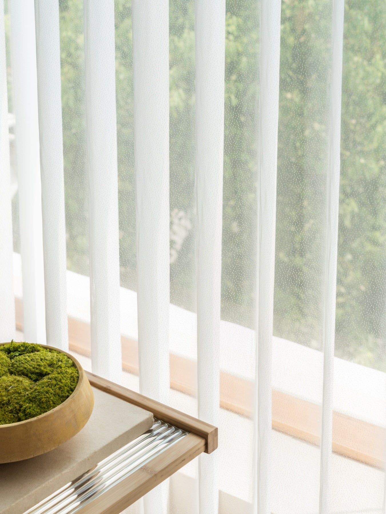Elegant white sheer curtains from EaseEaseCurtains allowing soft diffused light into a room with a decorative moss bowl on the sill, enhancing the airy and tranquil atmosphere of a sunlit living space