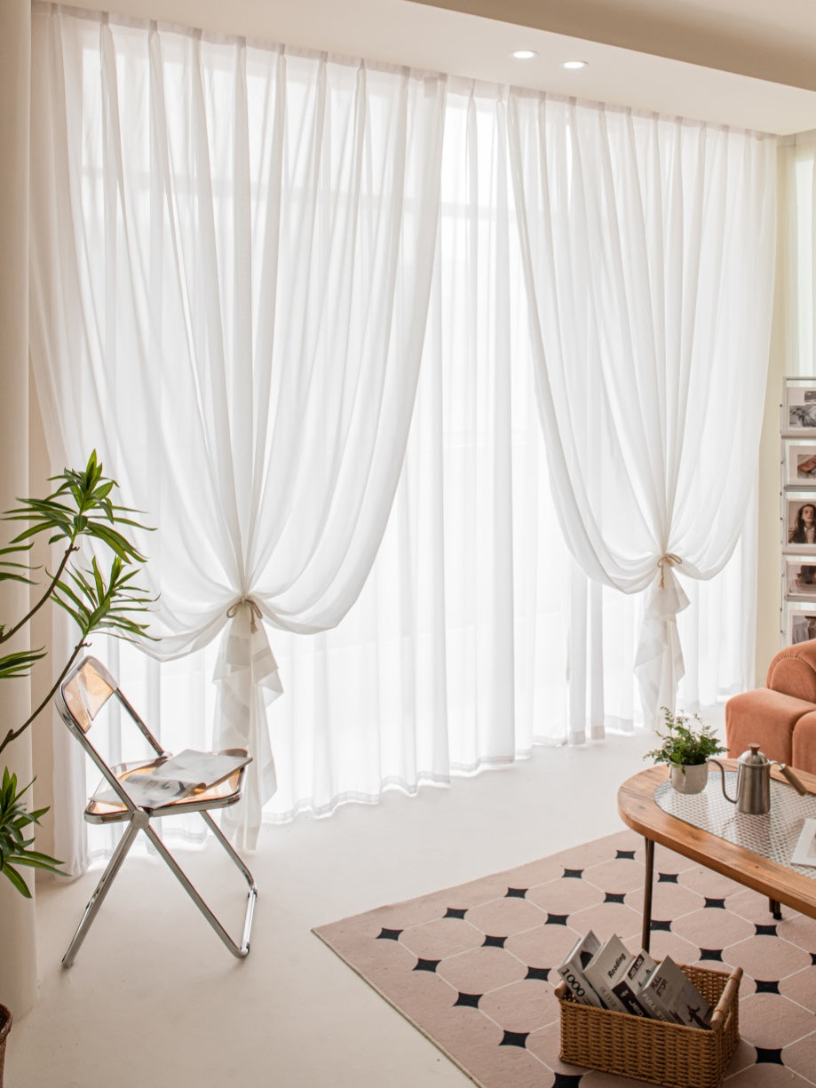 Elegant white gauze sheer curtains in a stylish living room with natural light, wooden furniture, and soft decor accents, enhancing a modern yet cozy atmosphere