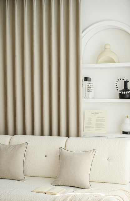 A white couch with pillows and a shelf. Luxurious cashmere texture blackout curtains add coziness to the living space.