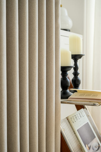 A book on a table by a window, with elegant EaseEase Luxurious Cashmere Texture Blackout Curtains hanging.