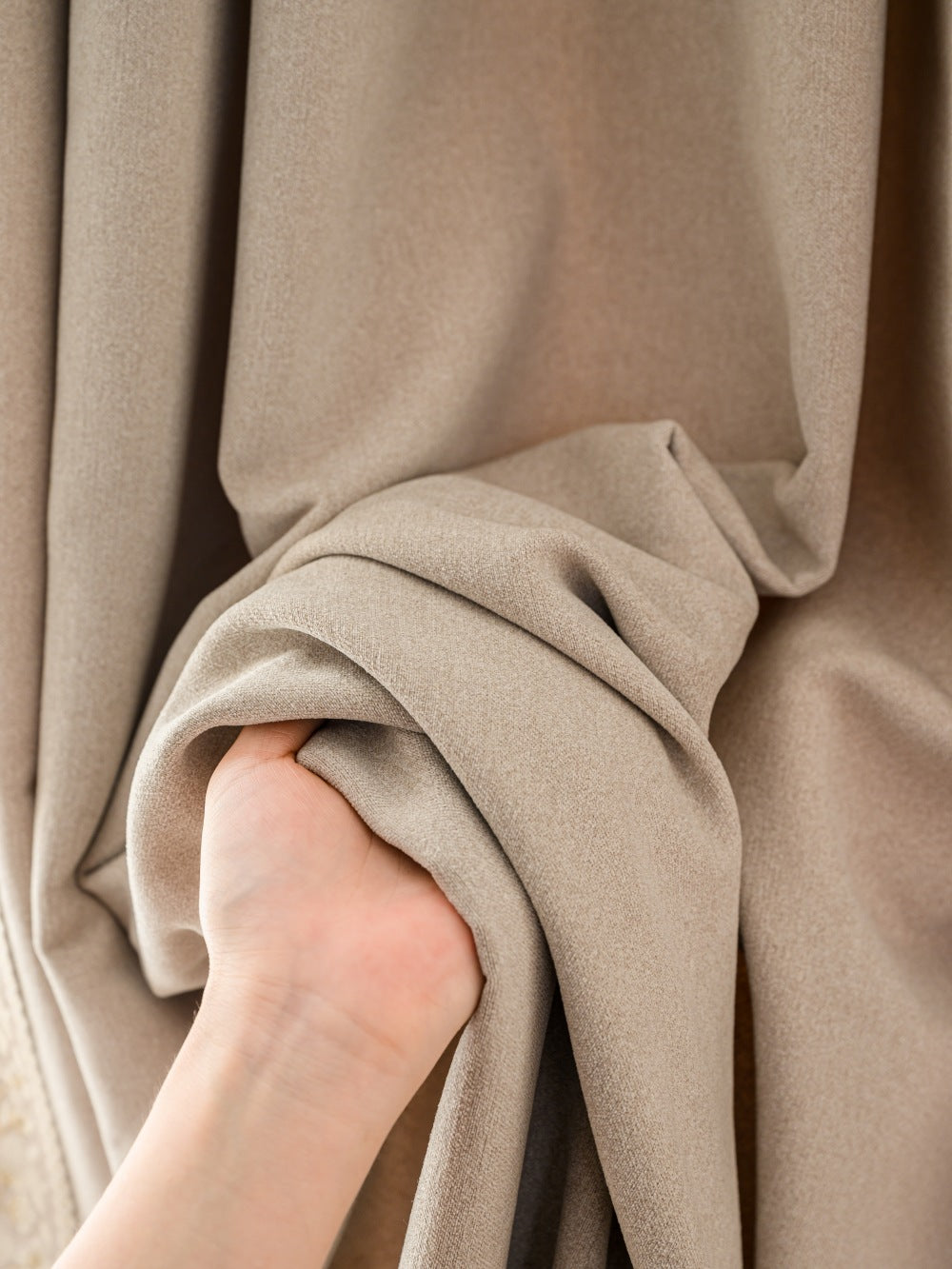 Close-up of hand demonstrating the plush texture of beige faux cashmere blackout curtains from EaseEaseCurtains