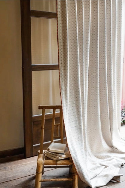 Light cream vintage curtains with subtle dot pattern draped beside wooden chair and door, showcasing elegant classic style
