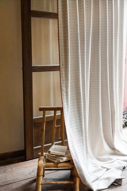 Light cream vintage curtains with subtle dot pattern draped beside wooden chair and door, showcasing elegant classic style