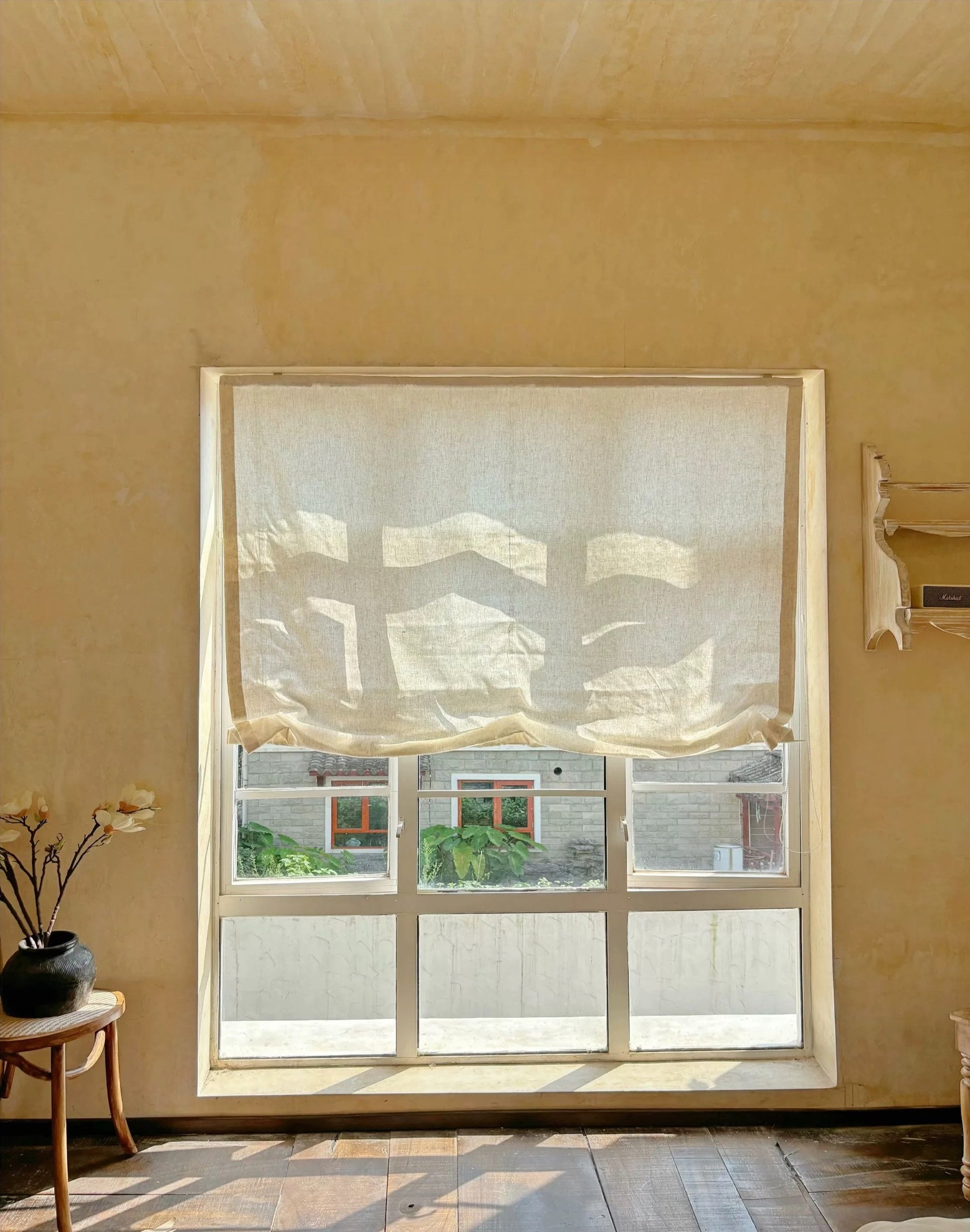 Relaxed roman shades filtering light in French-style interior.