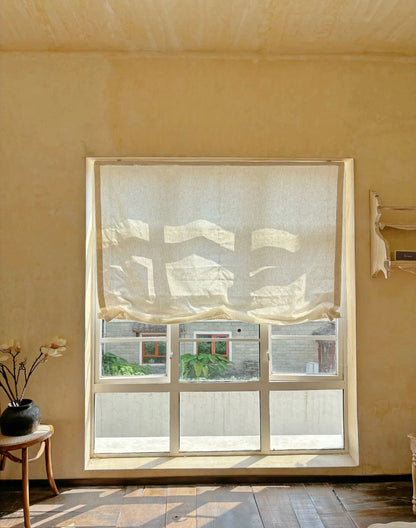 Relaxed roman shades filtering light in French-style interior.