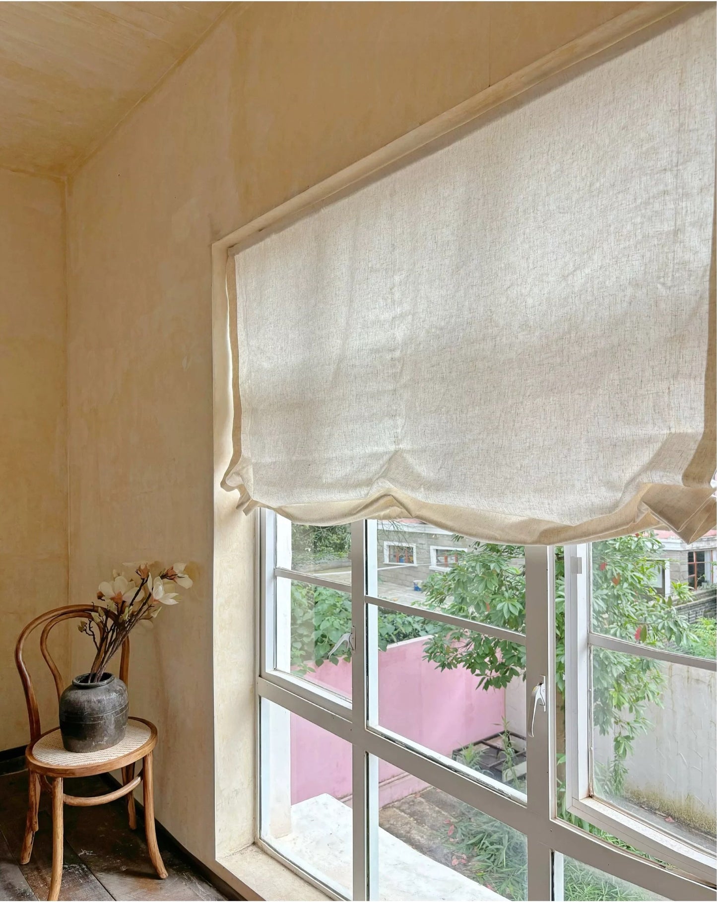 Relaxed Roman shades in premium linen, filtering light, with graceful curves adding elegance to French-style interiors.