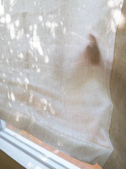 Relaxed Roman Shades in premium linen gauze filtering soft natural light.