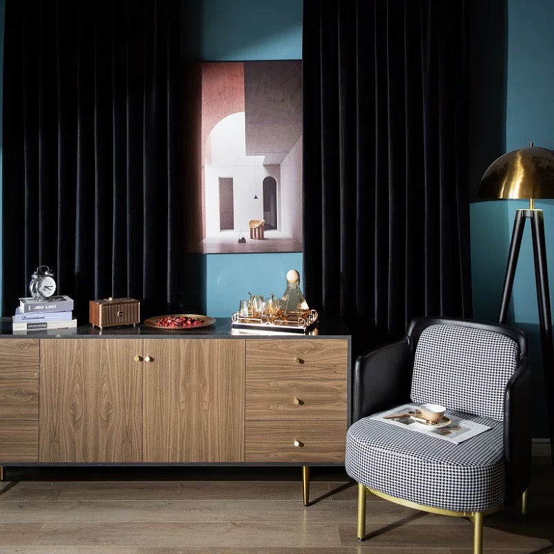 Elegant black velvet drapes in living room with wooden cabinet and patterned armchair