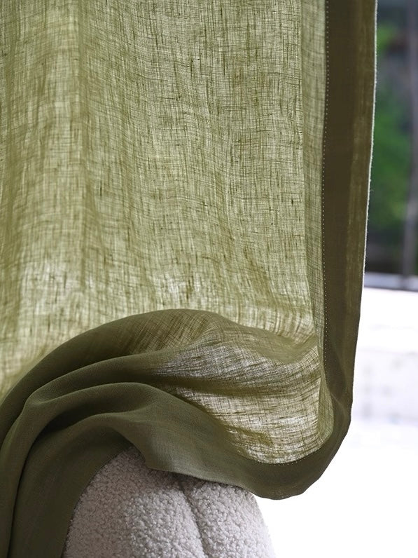 Close-up of sage green linen curtains with natural texture and light filtering through fibers