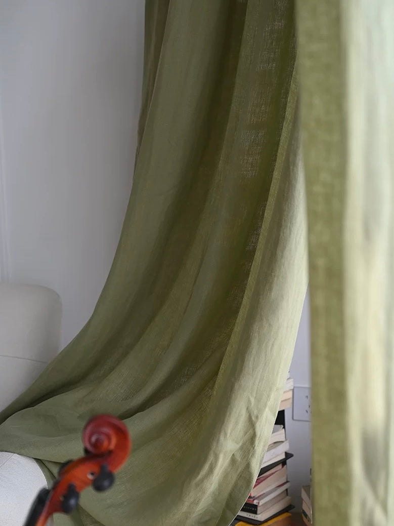 Sage green linen curtains draping softly in living room with natural light and cozy decor