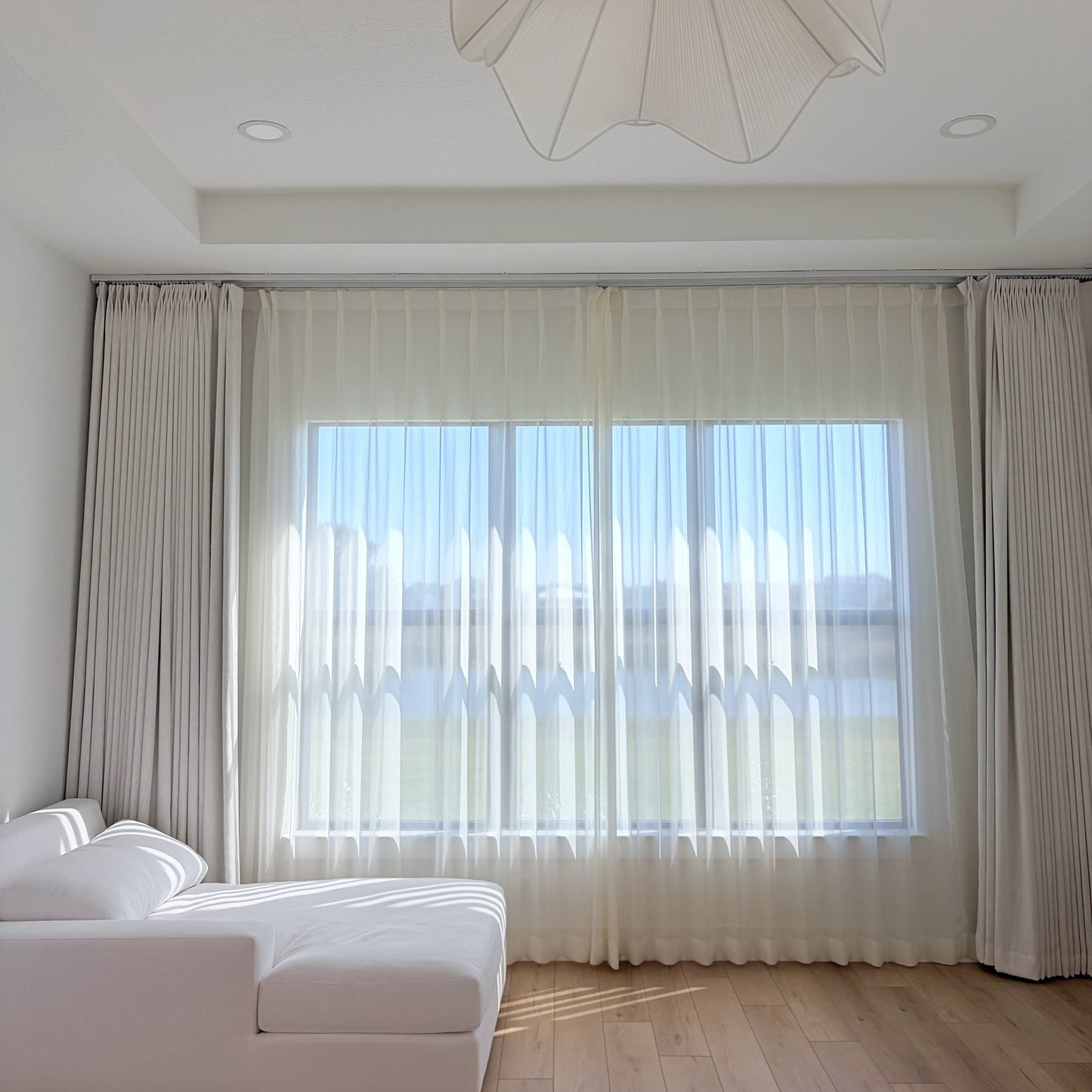 cream and white sheer curtains with radiant shimmer in bright sunroom over sofa