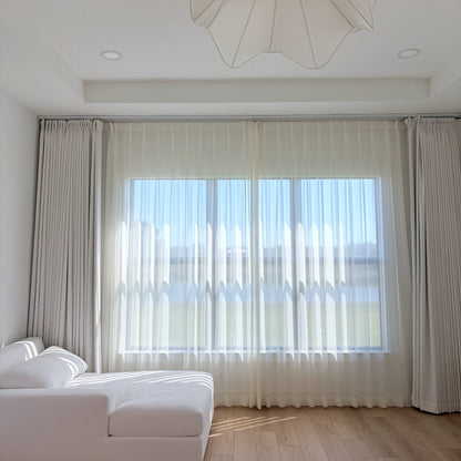 cream and white sheer curtains with radiant shimmer in bright sunroom over sofa