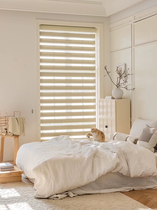 Stylish bedroom with Zebra Roller Shades providing a striped light effect, featuring a cosy bed with a small dog and elegant room accents