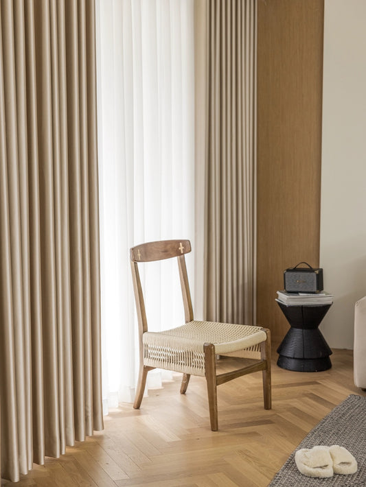 Elegantly draped beige and sheer white curtains in a serene room setting with a wooden chair and decorative lantern, showcasing the high-quality and stylish design of EaseEaseCurtains offerings