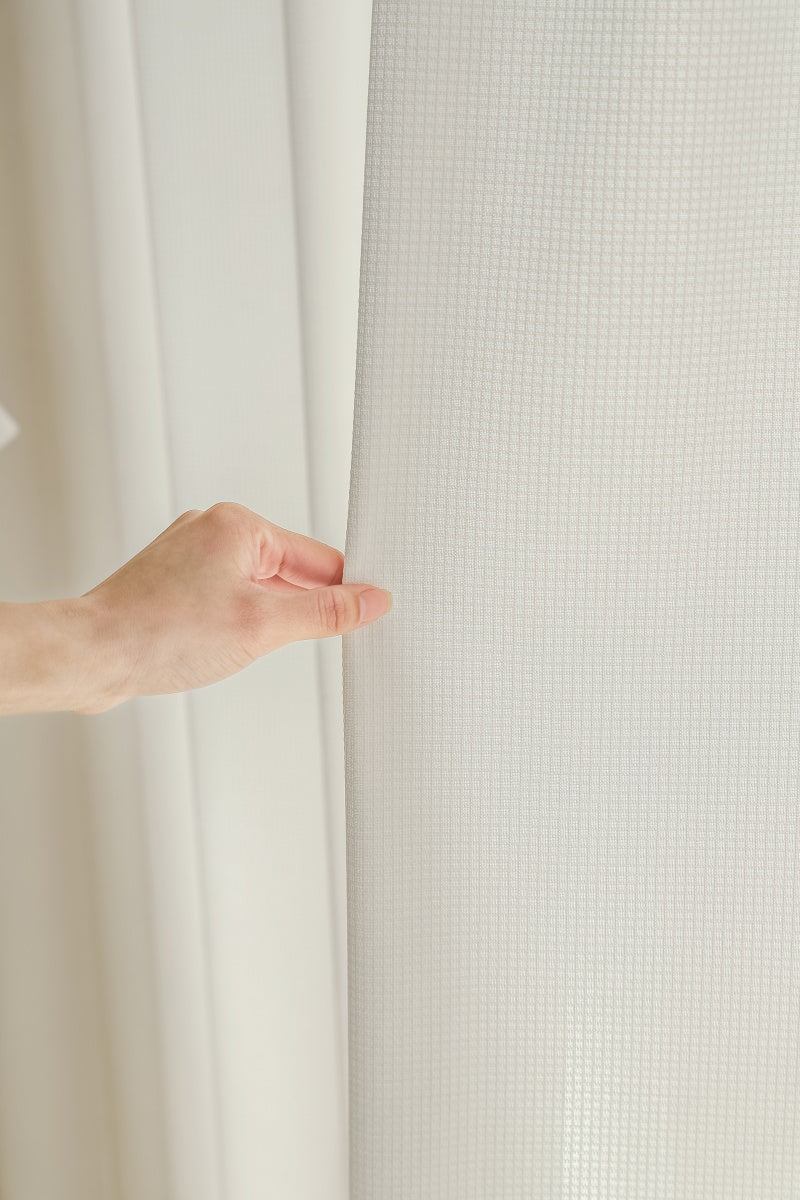 White curtain held by person, featuring UV protection and waffle pattern.
