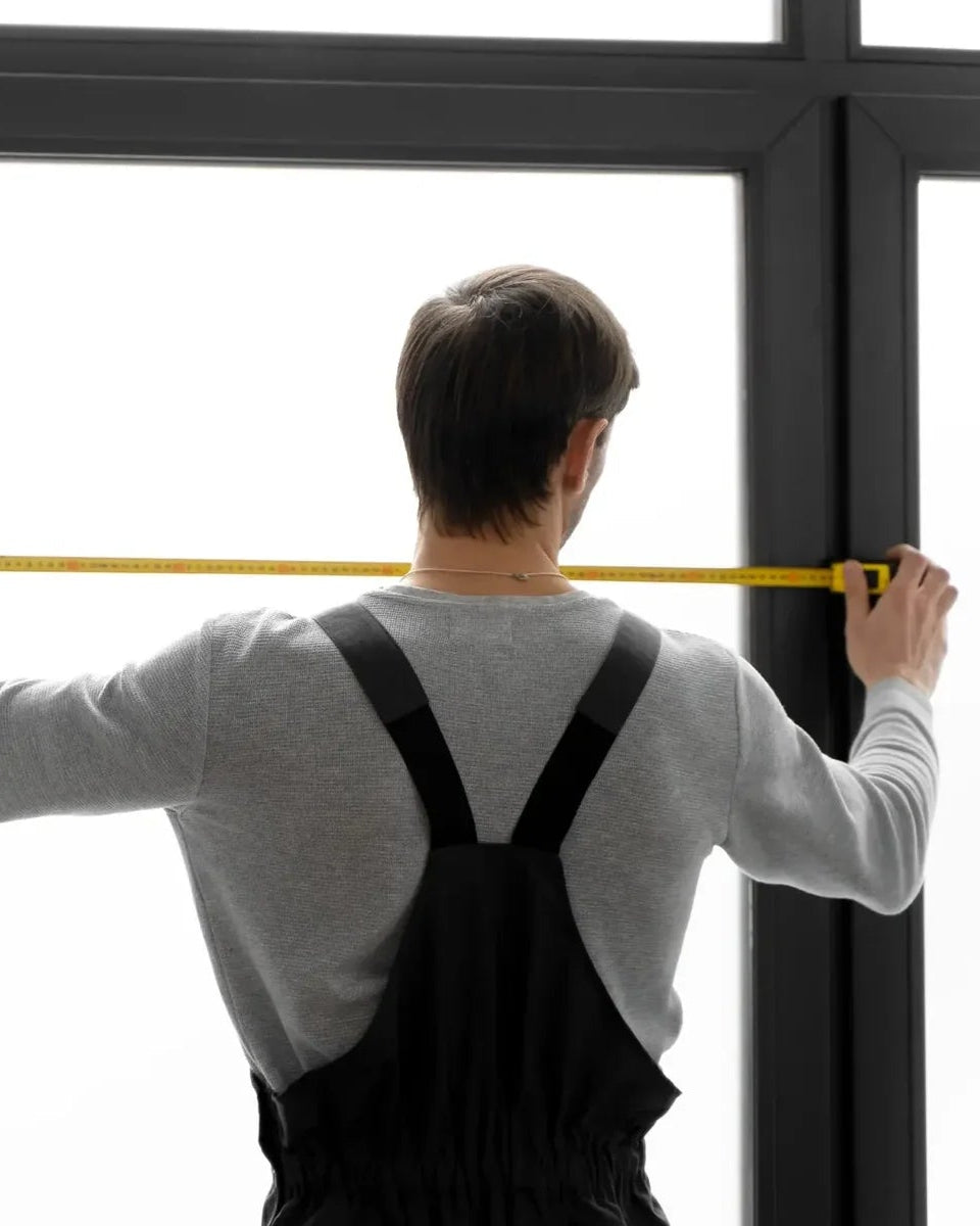 Person measuring a window with a tape measure