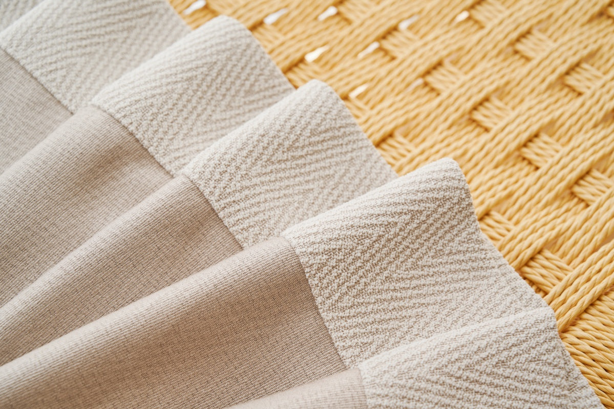 Close up of white and beige fabric with herringbone pattern, ideal for curtains.