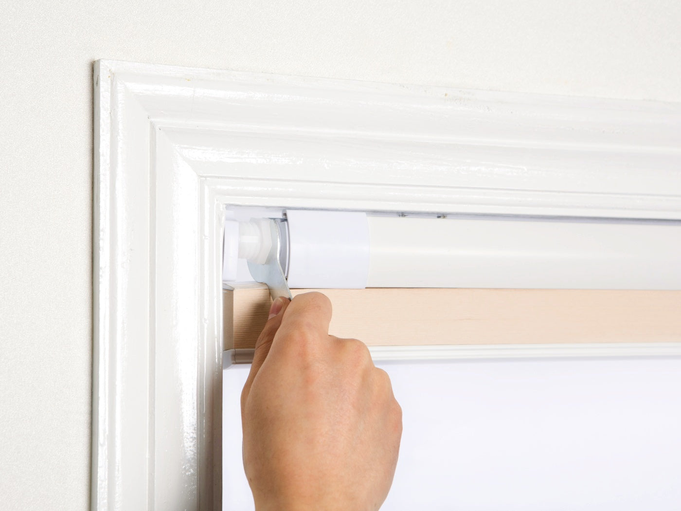 Tool-free no-drill honeycomb shades being installed on a window frame.