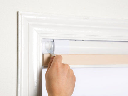 Tool-free no-drill honeycomb shades being installed on a window frame.