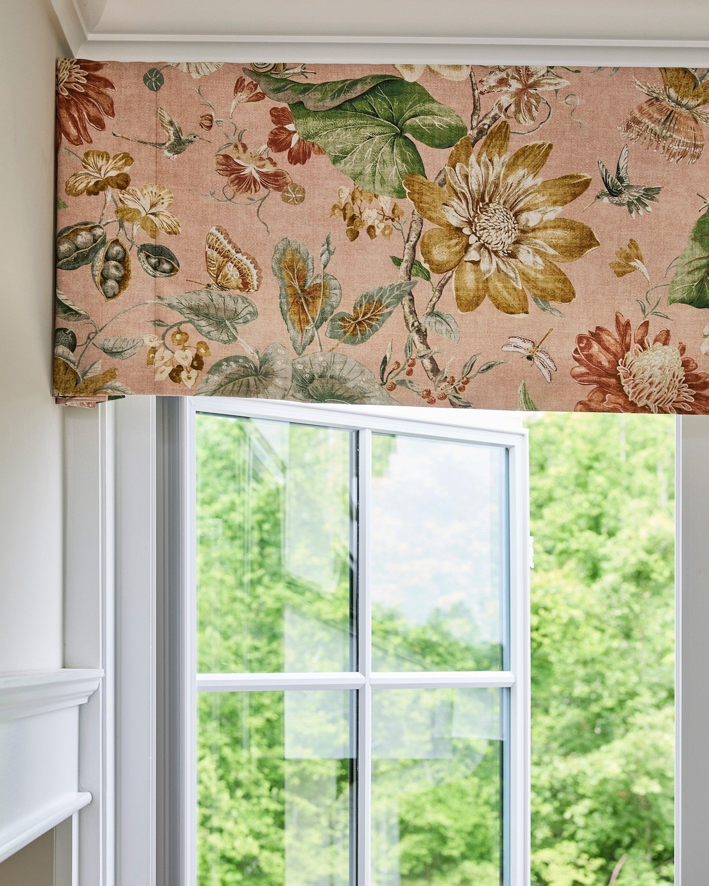 Patterned fabric Roman shade in flat fold style on window, featuring floral design, light filtering.