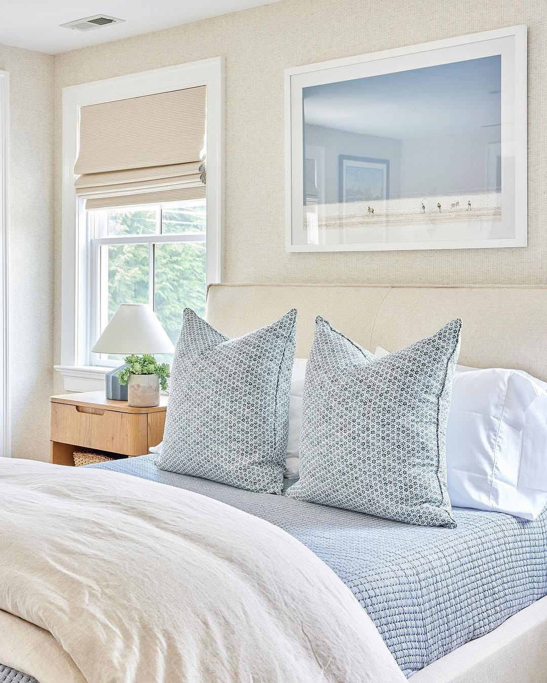 Patterned fabric Roman shades in a bright bedroom with elegant decor.